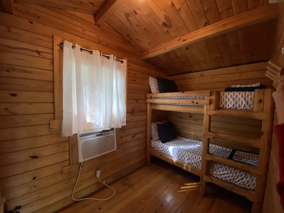 Wood-paneled cabin interior with bunk beds and air conditioning