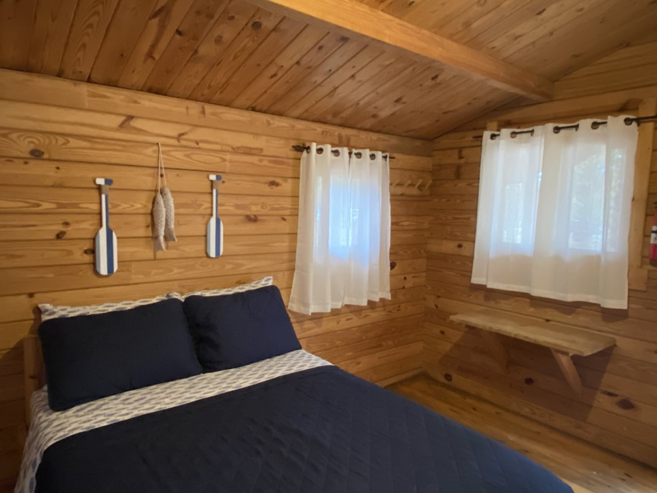 Wood-paneled cabin interior with a bed and window